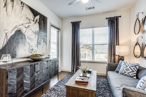 a living room with a gray couch and a painting of a horse